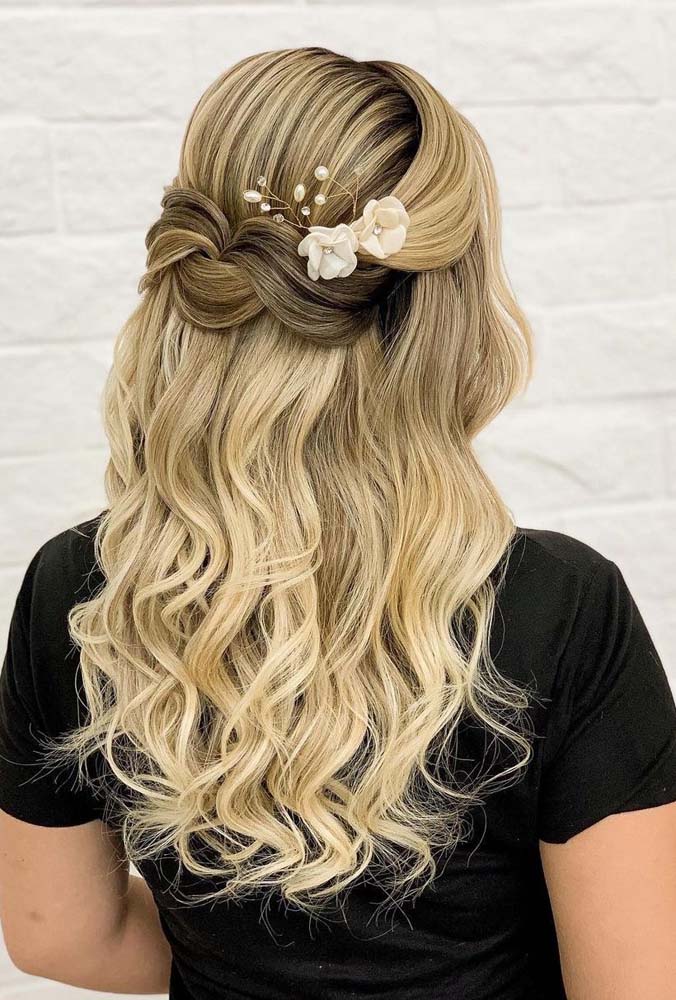 Muitas ondas nesse penteado para cabelo médio semi preso, com as mechas grossas da frente se cruzando na parte de trás do cabelo e o restante dos fios caindo como uma cascata nas costas. 