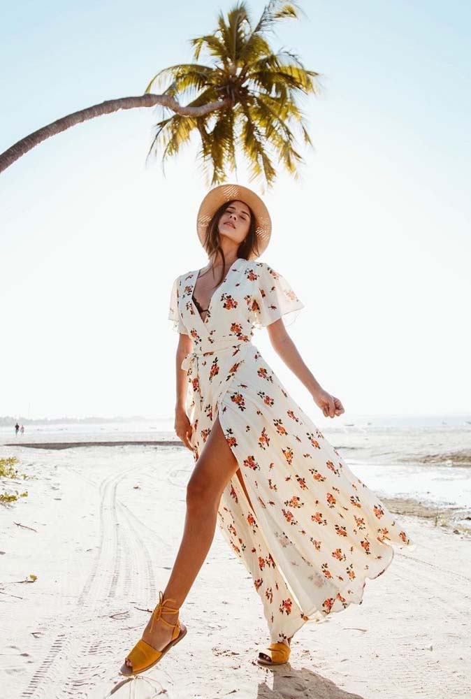 Saída de praia longa branca com estampa florida, manga curta soltinha: fechada, ela forma uma longa fenda na frente. 