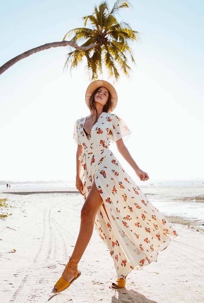 Saída de praia longa branca com estampa florida, manga curta soltinha: fechada, ela forma uma longa fenda na frente. 