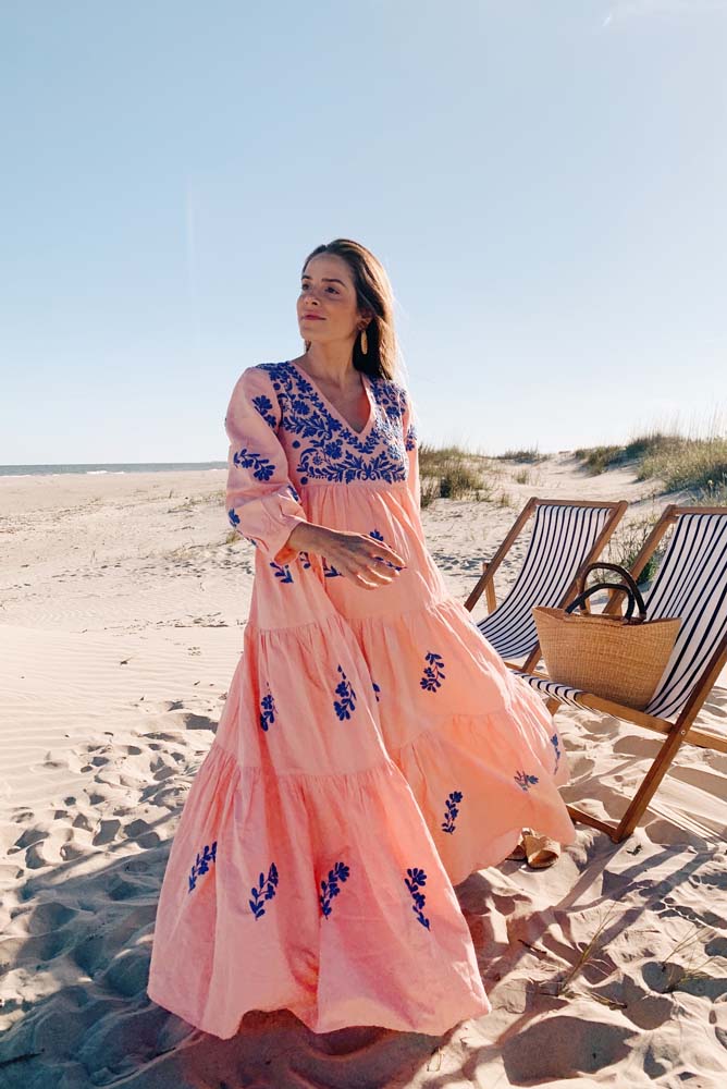 Look praia no estilo boho chic com saída de praia longa tipo túnica rodada rosa claro com bordados com motivos florais em azul anil. 