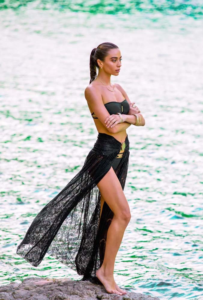 Um look fashionista all black para você se inspirar neste verão: saída de praia longa tipo saia rendada e biquíni sem mangas, ambos com detalhes em dourado.