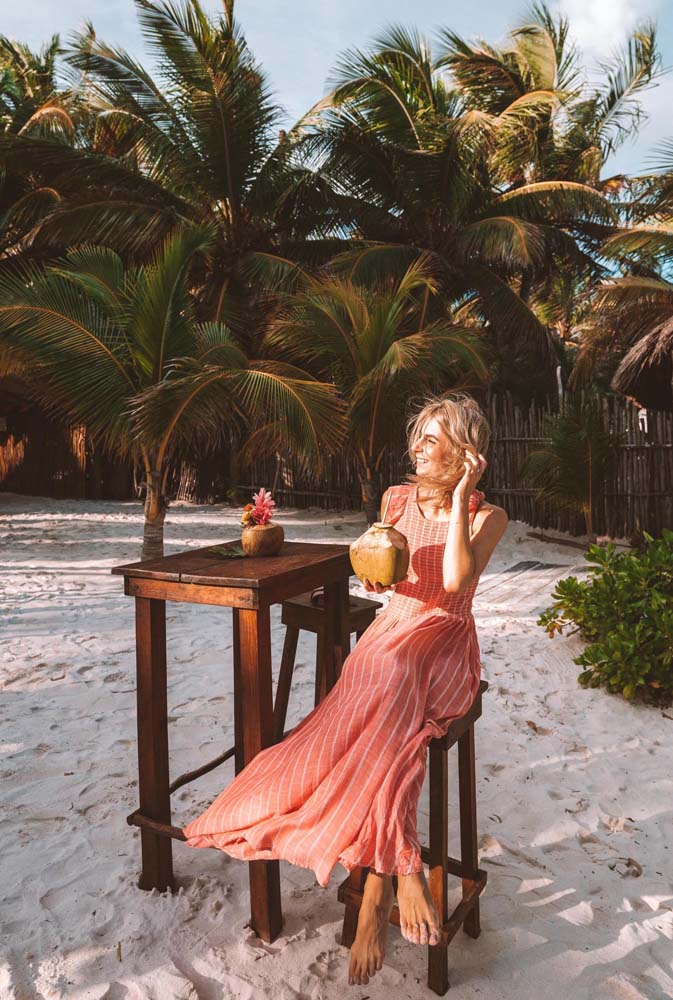 Esse vestido longo sem mangas de linho listrado faz um visual charmoso para assistir o pôr do sol na praia se refrescando com uma água de coco.