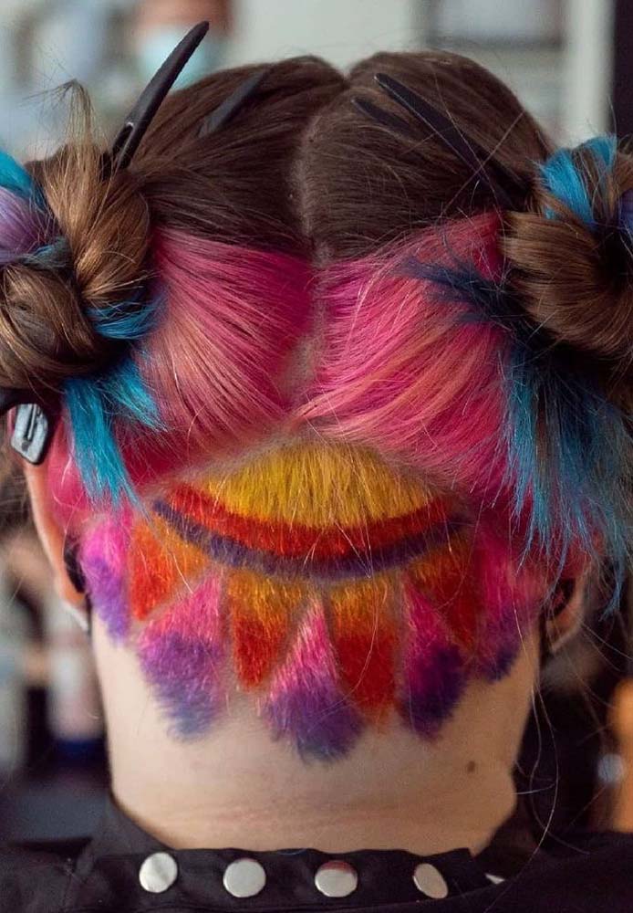 Mais uma ideia de undercut com desenho, dessa vez com um sol que combina com as mechas coloridas da parte de trás do cabelo e é revelado no penteado double bun.