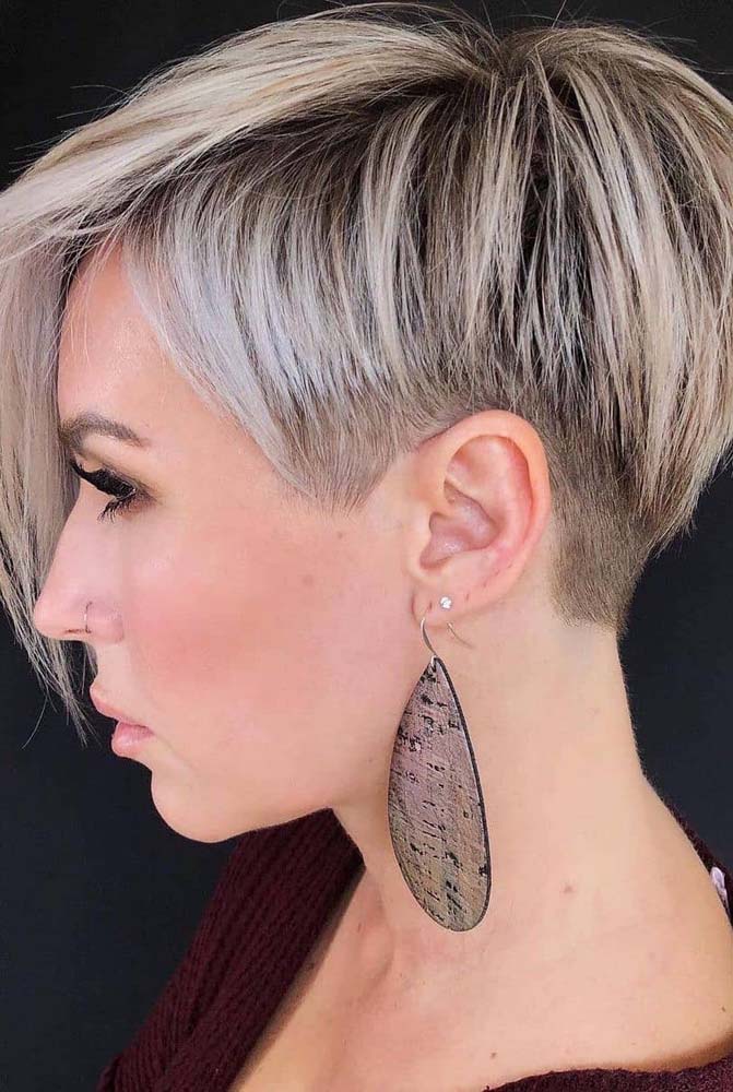 Corte pixie com franja lateral longa e undercut feminino bem baixinho na região da nuca e costeletas.