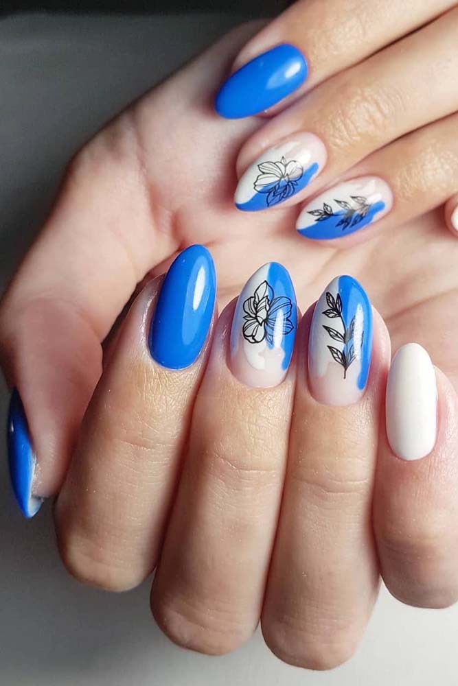 Outra ideia de unhas decorada azul celeste e branco, dessa vez com as duas cores se encontrando nas unhas gêmeas, finalizadas com um adesivo com desenho floral estilizado.