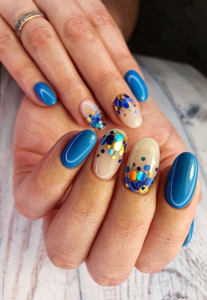 Uma composição bem festiva e alegre com esmalte azul celeste cobrindo as unhas, exceto pelas gêmeas, que ganham confetes coloridos e metalizados sobre o fundo clarinho. 