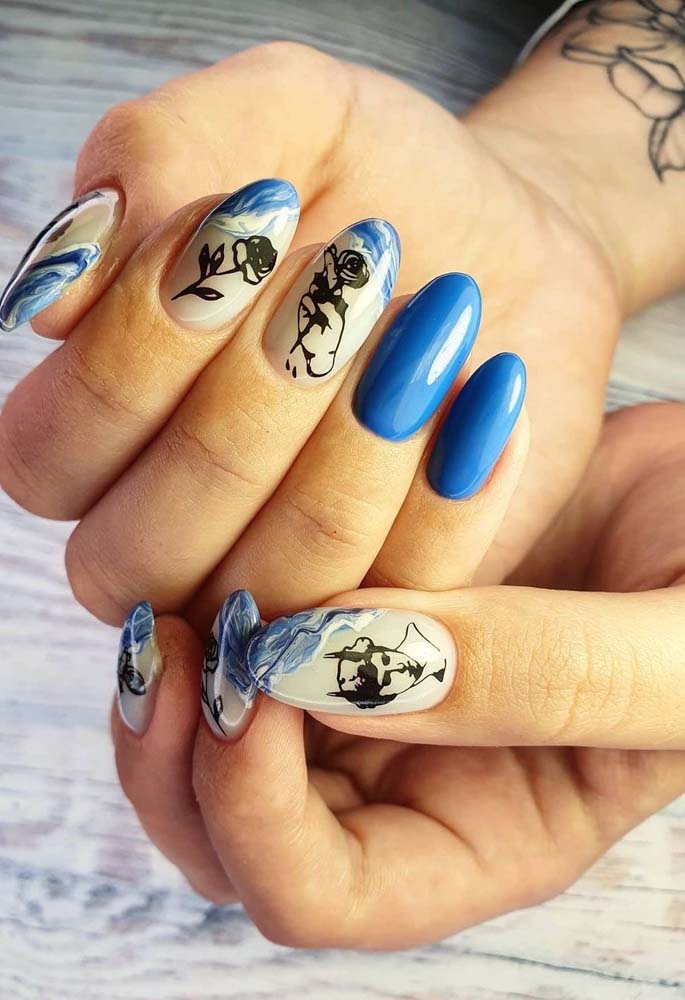 Mais uma ideia de unhas decoradas azuis inspiradas no mar, que aparecem na francesinha cheia de ondas e um destaque para os adesivos com desenhos variados em preto.