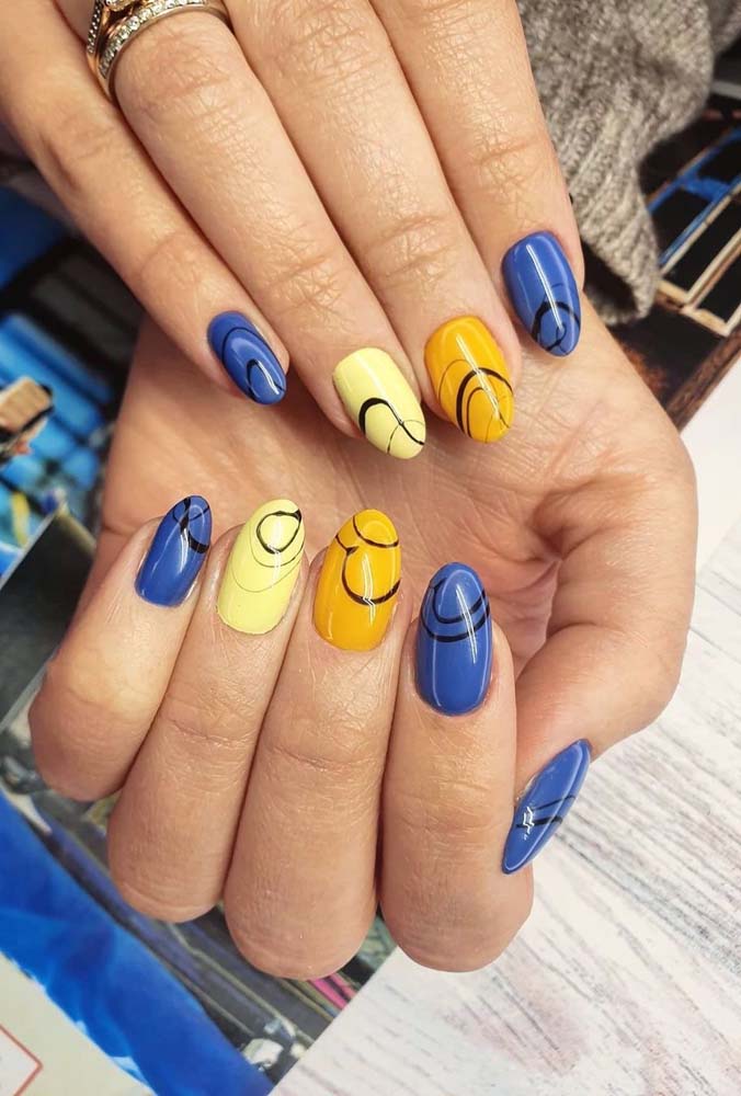 Outro tom primário, o amarelo faz uma combinação super alegre com o azul, como você pode ver nessa composição de unhas decoradas. 