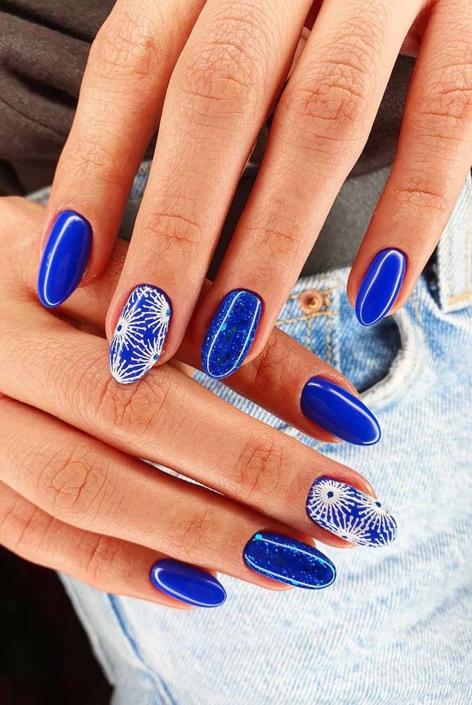 Outra combinação bem vibrante: unha azul com filha única decorada com adesivos de mandalas brancas.