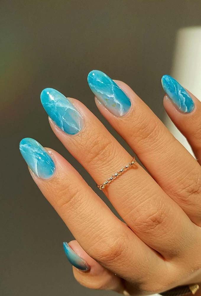 A pintura aquarelada e os toques de branco em linhas irregulares fazem com que essas unhas decoradas azuis turquesa garante um efeito marmorizado perfeito.