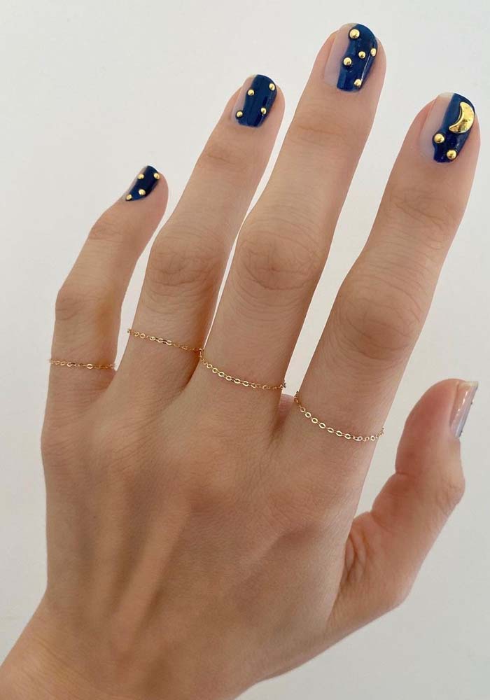 Suas unhas decoradas azuis inspiradas no céu estrelado não precisam ser totalmente escuras e profundas: confira essa ideia de half nails índigo com aplicação de jóias douradas. 