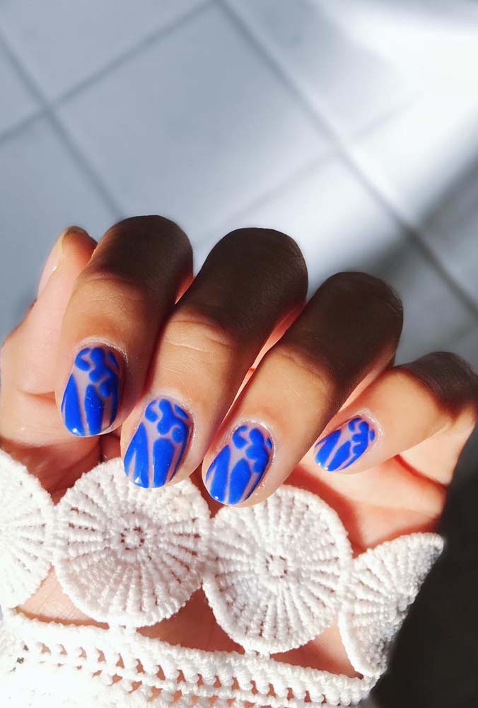 Você também pode usar o esmalte azul royal para fazer um padrão único por cima da base transparente das unhas.