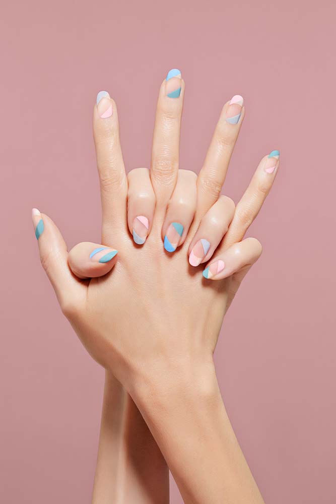 Outra forma de embarcar na tendência das half nails é fazendo uma divisão diagonal, como nessas unhas decoradas azul e rosa além do centro natural. 