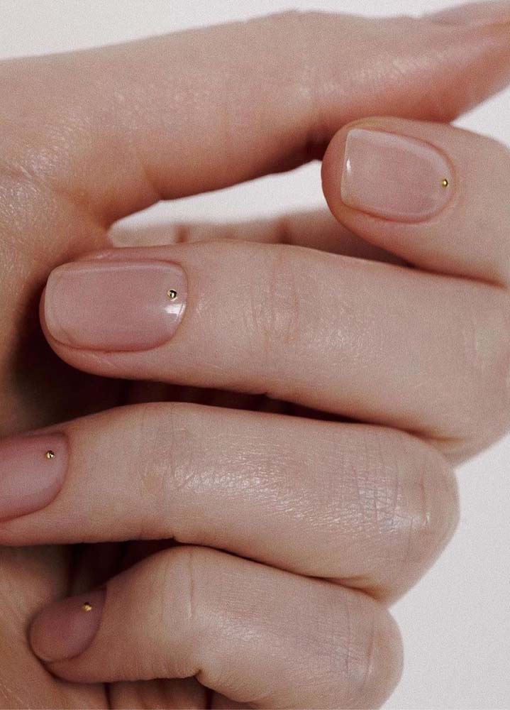 Unhas simples e delicadas em tom nude com mini strass dourado na base. É ou não é para se apaixonar?