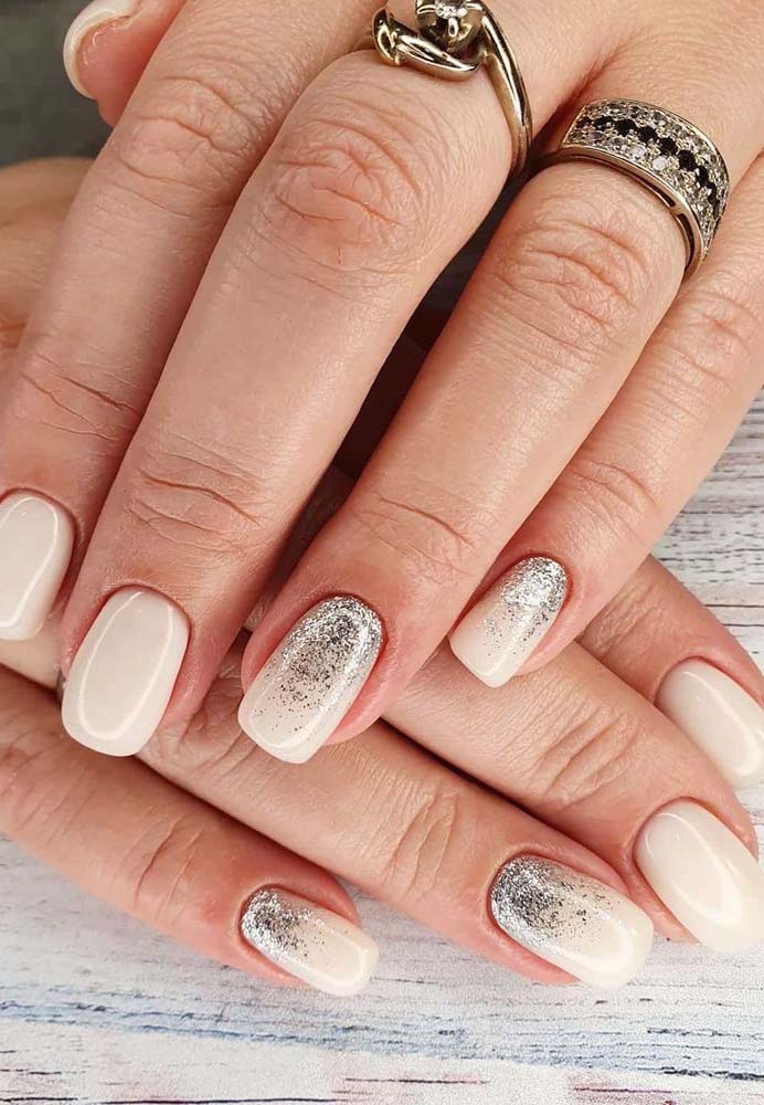 Unhas decoradas com glitter prata em contraste com o esmalte branco: simples e bonito