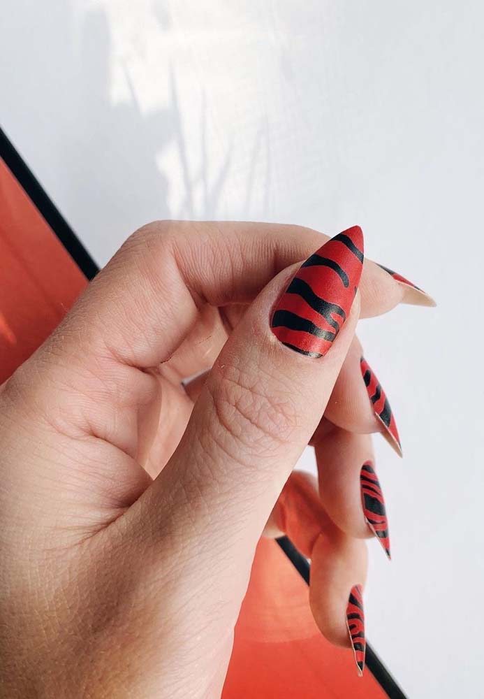 E por falar em animal print, uma ideia de unhas vermelhas com preto no formato stiletto 